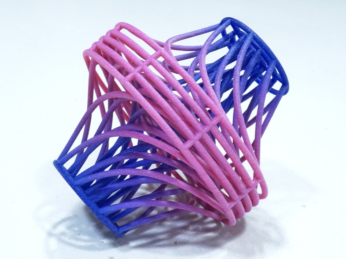 A 3D-printed sculpture of curved strands that shade from pink to blue, twisting between two square frames along the streamlines of a vector field