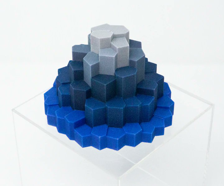 A Riemannscape sculpture: a stepped mound of hexagonal columns that shade from bright blue at the base to light gray at the top
